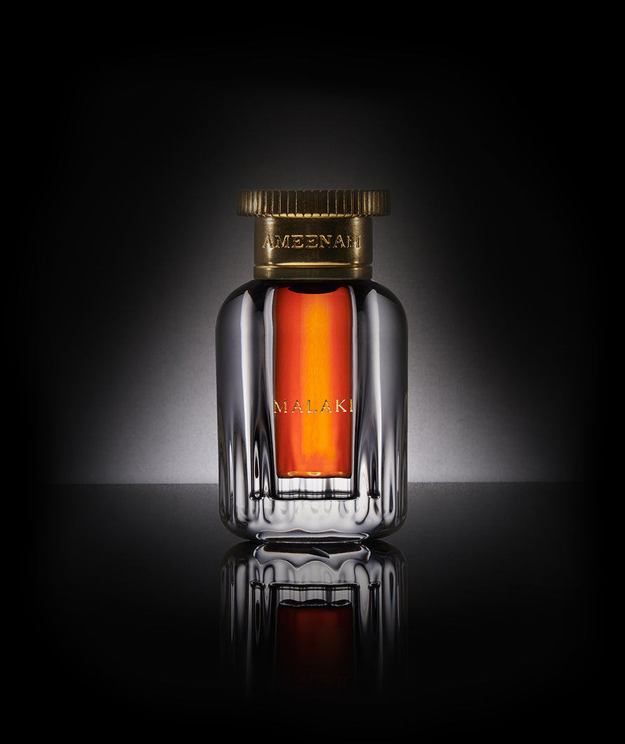 Close-up of Ameenah Malaki Dehn Al Oud bottle, a royal oud oil with woody and vanilla notes, crafted from Thai Aquilaria trees.